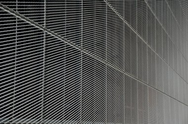 Genişletilmiş metal kafes yapısı olan bir binanın çelik kaplaması. Galvanize gri ağlar endüstriyel binayı koruyor. Gümüş arkaplan ve duvarın aksine mavi gökyüzü