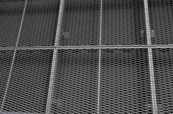 steel cladding of a building with a expanded metal lattice structure. galvanized gray nets protect the industrial building. Blue sky in contrast to a silver background, wall