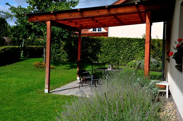 terrace with wooden pergola and plexiglass roof. vines are straining, crawling under the beams. garden or park. sitting with dry wall wine region. restaurant countryside france