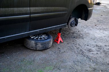 İç koşullarda arabada fren diski değiştirmek. Tamirci yıpranmış frenleri çıkarır ve yenilerini takar. Aletleri ve montaj yastığı var, dur, vale