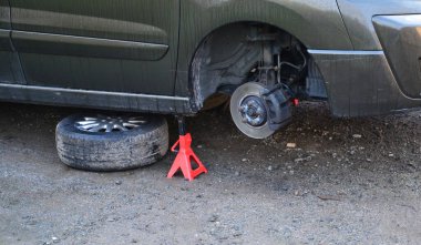 İç koşullarda arabada fren diski değiştirmek. Tamirci yıpranmış frenleri çıkarır ve yenilerini takar. Aletleri ve montaj yastığı var, dur, vale