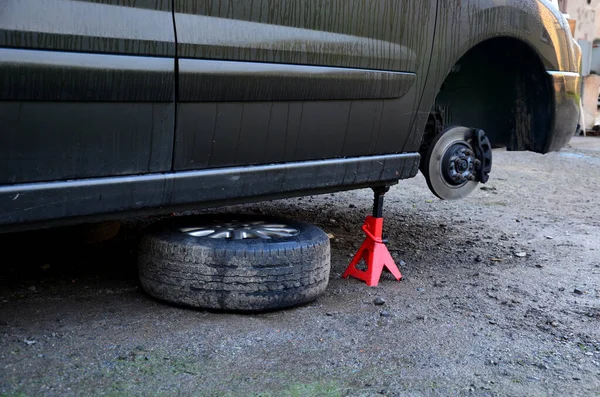 İç koşullarda arabada fren diski değiştirmek. Tamirci yıpranmış frenleri çıkarır ve yenilerini takar. Aletleri ve montaj yastığı var, dur, vale