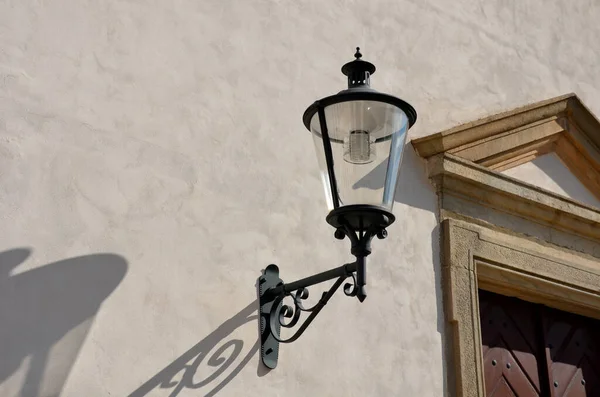 Historicizing style of lamp that is not gas but LED lights. Lantern frame without glass filling. historic city center with natural facade brown wooden door with arch