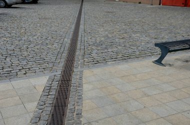 Patikanın karşısında, kanalizasyon borularını birbirine bağlayan metal bir kanal var. Su yüzeyden kanalizasyona, oradan da kanalizasyona çekilir.