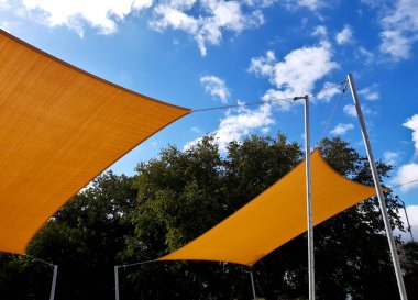 Kare tuval gerildi, güneş ve yağmurdan gölgelendi restoranın terasında, çocuk parkında, gezinti platformunda. Metalik gri kirişli pergola, kablo, elektrik, ampul,
