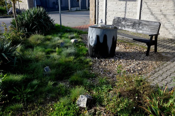 on the street a large log painted by children as a tree stump. table and bench behind a concrete fence. a meeting place for neighbors. playground where mothers drink coffee. candle lamp, lantern