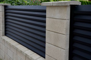 Beton bloklardan oluşan çitin metal dolguları. Metal bir alüminyum çit bahçede mahremiyet sağlayacak. Yatay kirişler iyi korunuyor. Tuji 'den yapılmış bir çit koruma sağlar.