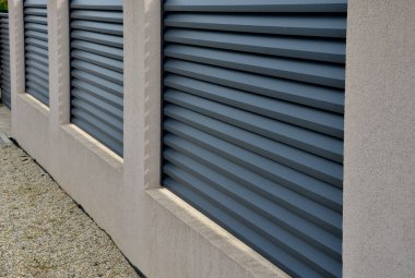 Beton bloklardan oluşan çitin metal dolguları. Metal bir alüminyum çit bahçede mahremiyet sağlayacak. Yatay kirişler iyi korunuyor. Tuji 'den yapılmış bir çit koruma sağlar.