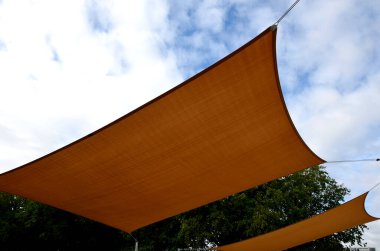 Kare tuval gerildi, güneş ve yağmurdan gölgelendi restoranın terasında, çocuk parkında, gezinti platformunda. Metalik gri kirişli pergola, kablo, elektrik, ampul,