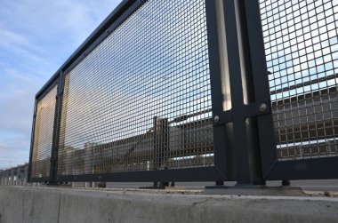 Genişletilmiş metal levha eskrimi. Galvanize parmaklıklardan yapılmış çok dayanıklı parmaklıklar. Süslü otların şeridi mekana insafsız bir bakış kazandırıyor. Izgara gibi yarı şeffaf
