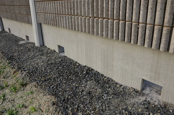 freeway bridge drainage. A sound-absorbing wall with holes lets water through. gutters collect water from gutter of water line. pipe with flexi rubber connection. slowing down flow of water roughening