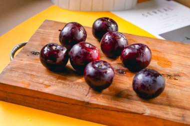 Kesme tahtasında taze siyah erikler