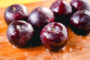 Kesme tahtasında taze siyah erikler