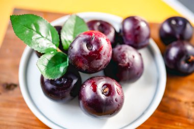 Kesme tahtasında taze siyah erikler