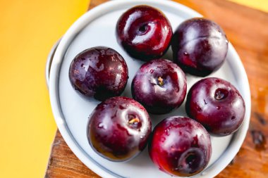 Kesme tahtasında taze siyah erikler