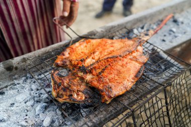 Köy ahşap sopalarla ızgara balık yapıyor.