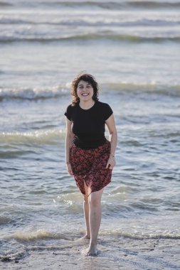 Genç kız sahilde ayaklarını ıslatıyor.