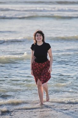 Genç kız sahilde ayaklarını ıslatıyor.