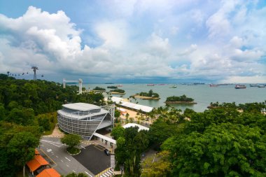 Beachfront on Sentosa Island, Singapore with dozens of container ships dotting the ocean in the background