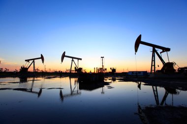 Petrol sahası, akşam, yağ pompaları çalışıyor, ışın pompalama ünitesi silueti