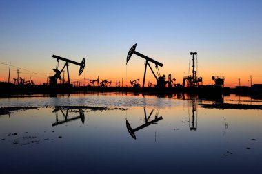 Petrol sahası, akşam, yağ pompaları çalışıyor, ışın pompalama ünitesi silueti