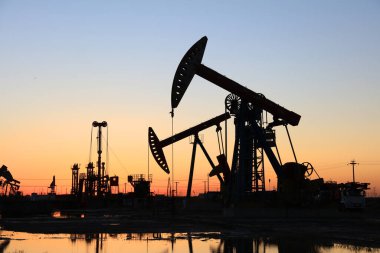 Petrol sahası, akşam, yağ pompaları çalışıyor, ışın pompalama ünitesi silueti