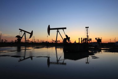 Petrol sahası, akşam, yağ pompaları çalışıyor, ışın pompalama ünitesi silueti