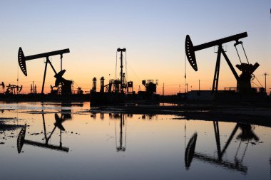 Petrol sahası, akşam, yağ pompaları çalışıyor, ışın pompalama ünitesi silueti