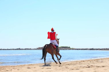 Sahilde dörtnala koşan yarış atı ve jokeyi, sahilde yarışan yarış atları ve jokeyleri