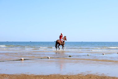 Sahilde dörtnala koşan yarış atı ve jokeyi, sahilde yarışan yarış atları ve jokeyleri