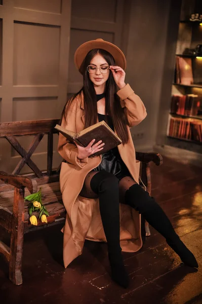 Beautiful Young Woman Hat Glasses Sitting Wooden Bench Room Book — Zdjęcie stockowe