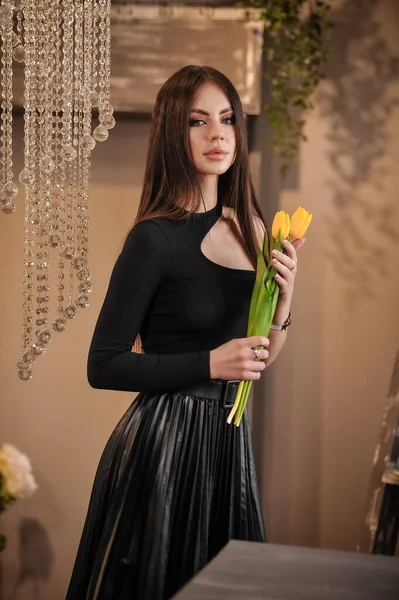 部屋に花の花束を持つ美しい若い女性 — ストック写真