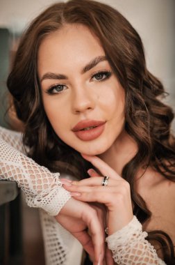 Uzun kıvırcık saçlı, beyaz elbiseli güzel bir kadın.