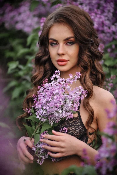 beautiful young woman with long hair in a pink dress in a garden