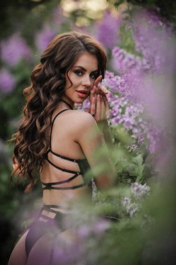 Uzun saçlı, mor elbiseli, ormanda poz veren güzel bir kadın.