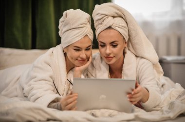 beautiful young women with her daughter in bathrobe and towel on bed in bedroom