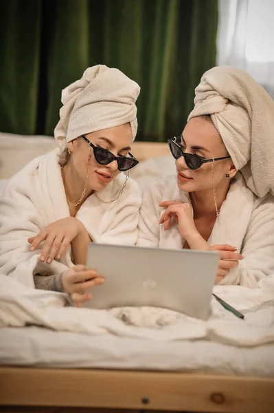 beautiful young women in bathrobes and bathrobe with laptop and coffee in hotel room