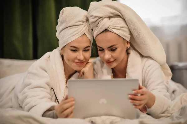 beautiful young women with tablet and towels in the bedroom