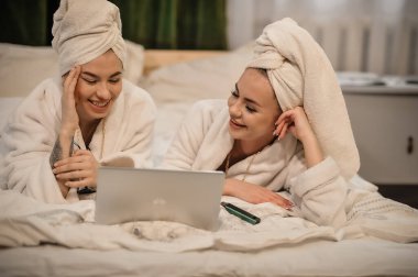 beautiful young women with towel and towels in bed