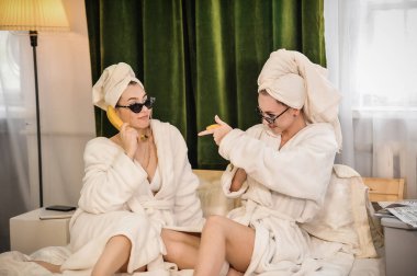 Gözlerinde havluyla bornozla oturan iki güzel kız.