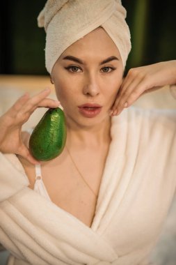 Kafasında havluyla kameraya bakan güzel genç bir kadın.