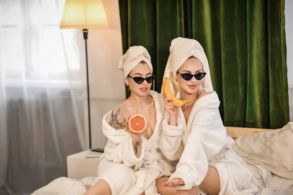 two women in bathrobes and bathrobe having fun in spa salon