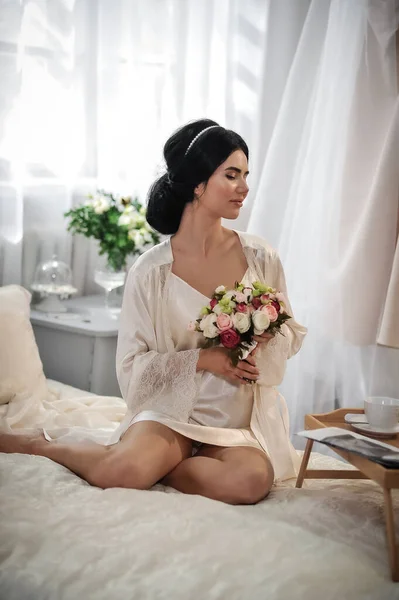 美丽的年轻女子 长发白衣坐在床上 开着花 — 图库照片