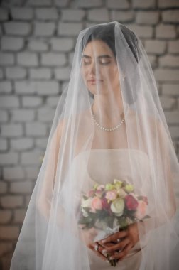 Duvağı ve düğün buketi olan güzel gelin