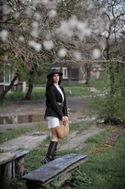 Sonbahar parkında poz veren şapkalı ve ceketli genç bir kadın.