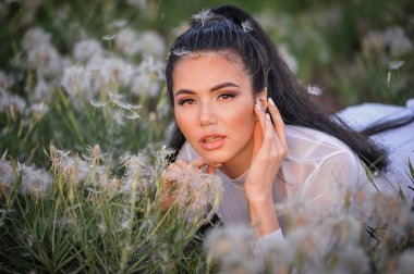 Çimlerin üzerinde beyaz elbiseli güzel genç bir kadın.