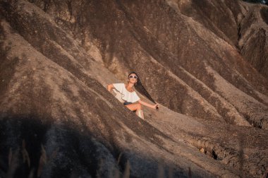 Kumsalda sırt çantalı siyah elbiseli genç bir kadın.