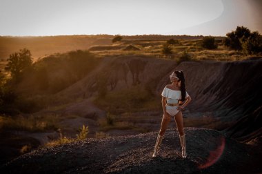 Kumsalda sırt çantalı siyah elbiseli genç bir kadın.