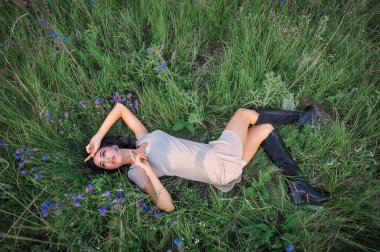 Yaz parkında çimlerin üzerinde uzanan güzel genç bir kadın.