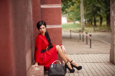 young beautiful woman in a red dress and a black jacket and a bag of coffee